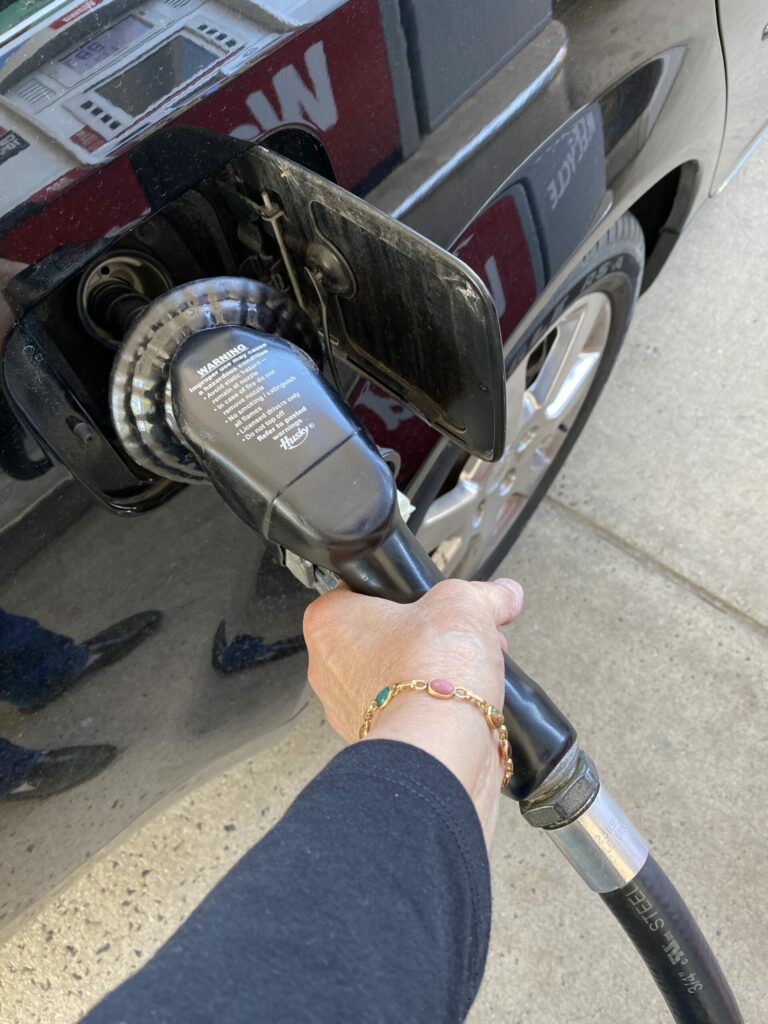 hand-hand-in-frame-pumping-gas-parked-car-gas-station-filling-up-outdoors-gas-pump_t20_42LPxl